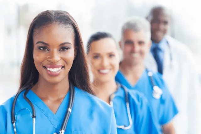Diverse healthcare professionals in blue scrubs smiling confidently.
