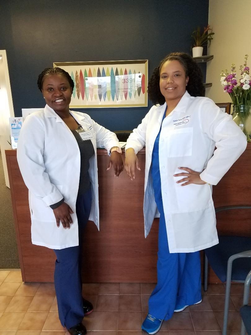 Two female medical professionals smiling in a clinic lobby.